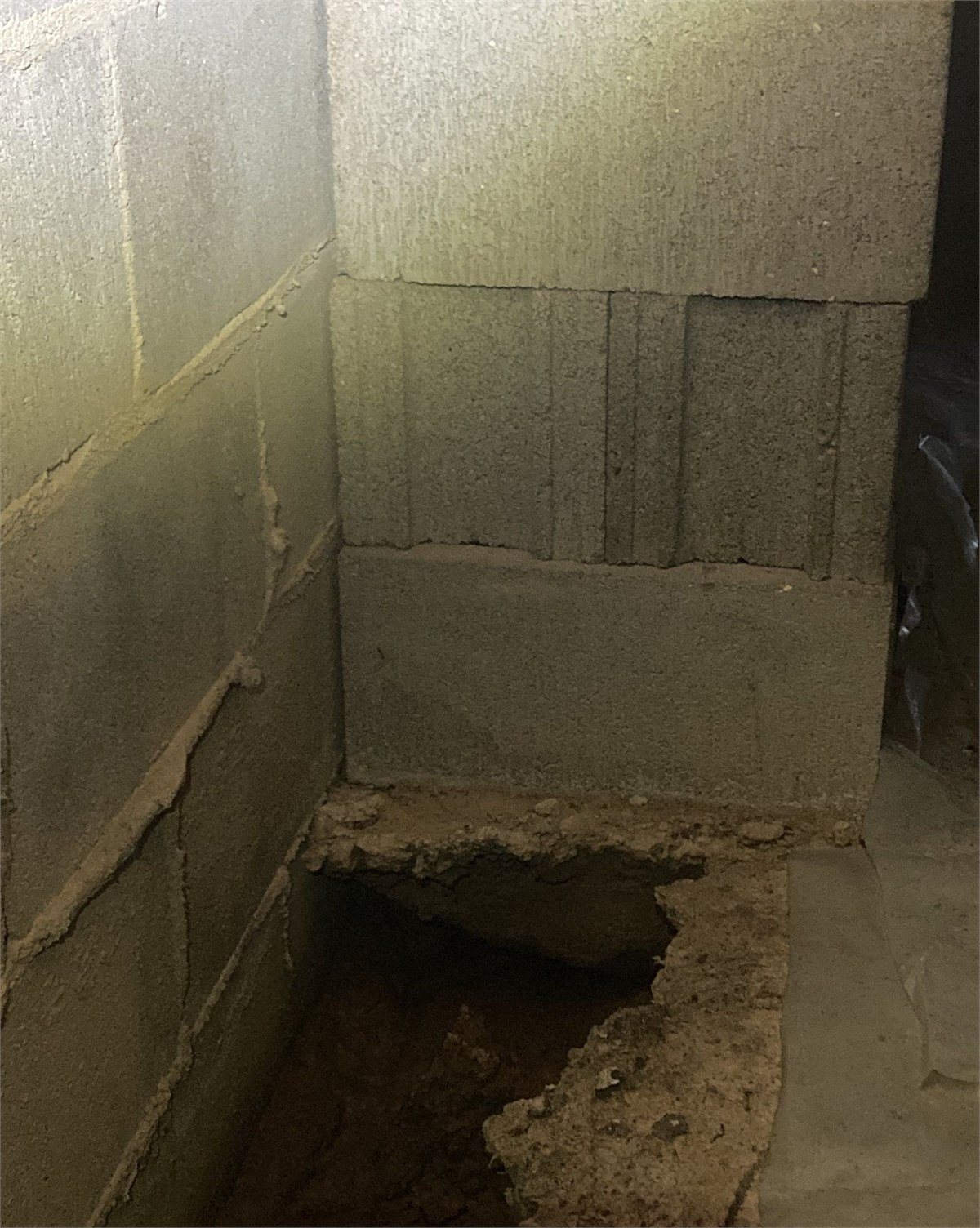 Soil erosion visible beside a crawlspace foundation support area