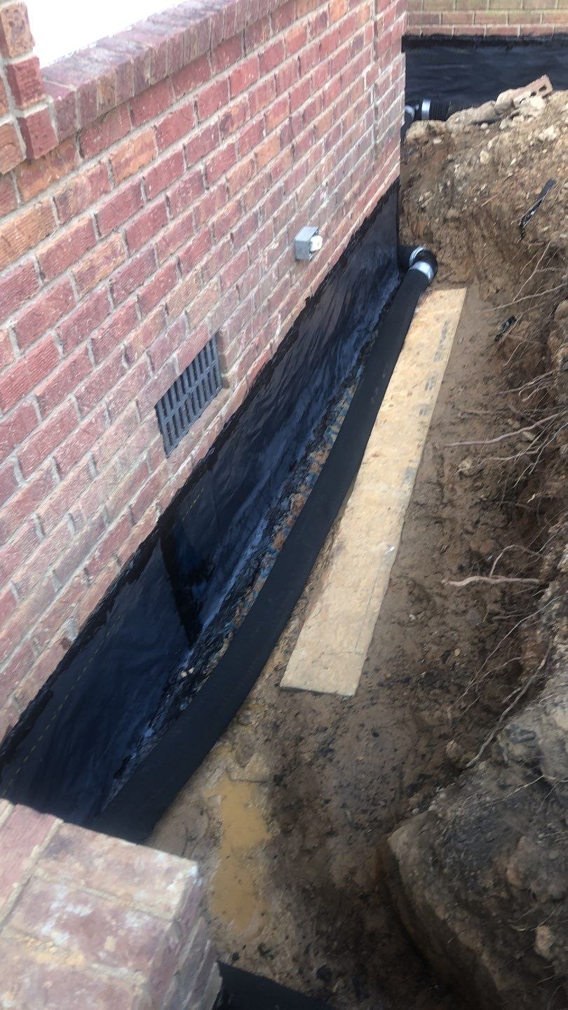 Exterior waterproofing installed along an exposed foundation wall