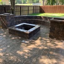 Finished retaining wall incorporated into a paved outdoor fire-pit and gathering area