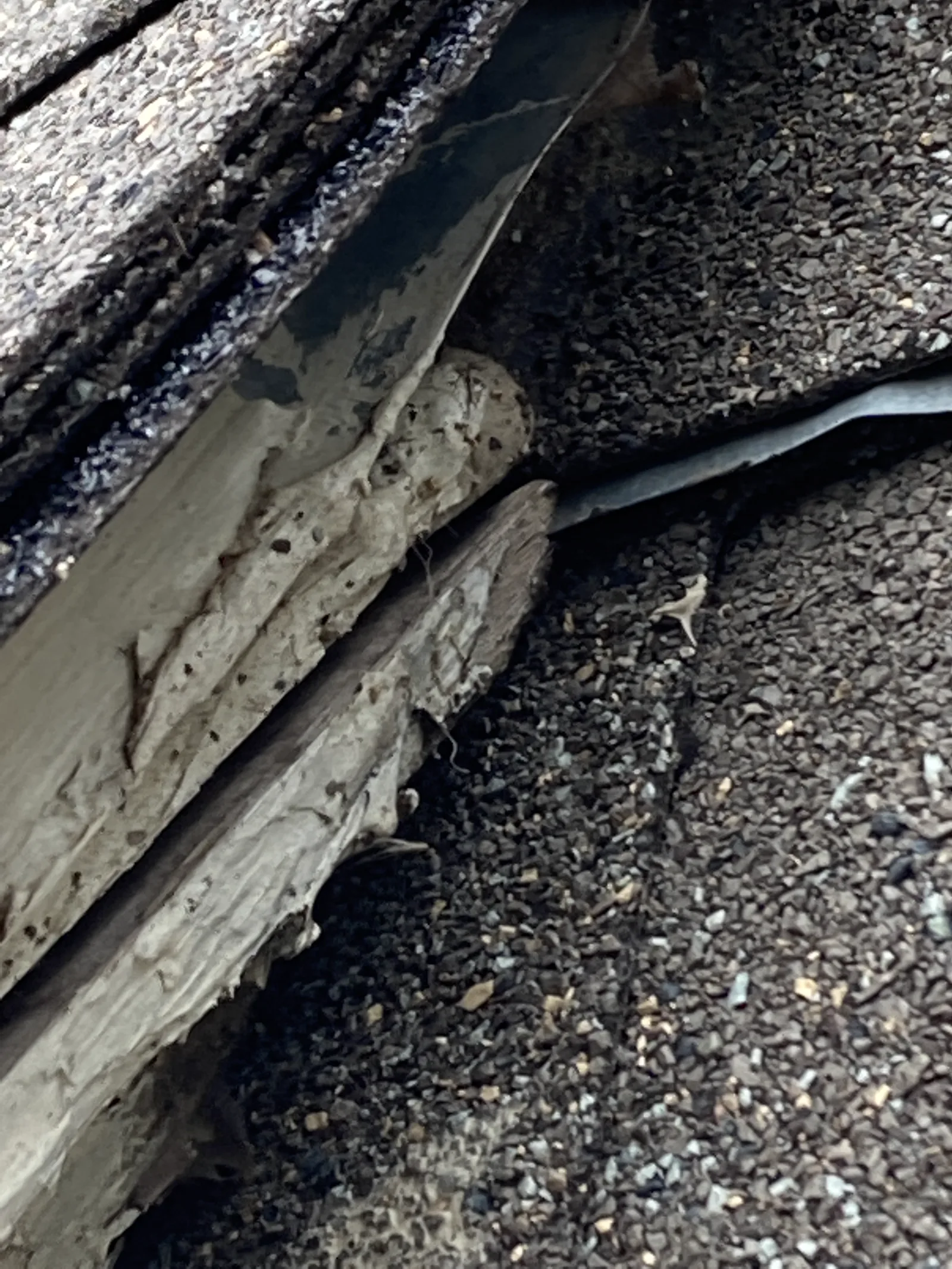 Water-damaged wood at a roof transition where adjoining roof surfaces meet.