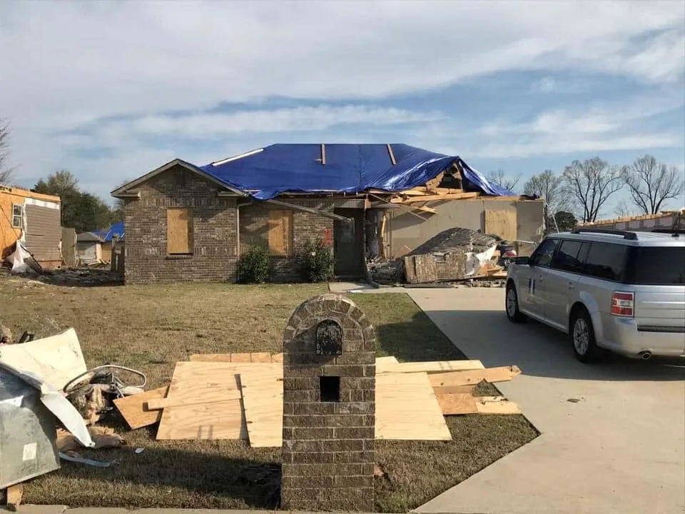 Tornado-damaged Northeast Arkansas property protected by a temporary roof tarp before permanent restoration
